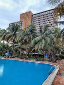 a large hotel with palm trees in front of a pool at GRANADA l'Amitié in Bamako