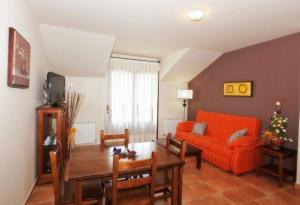 a living room with an orange couch and a table at Apartamentos Pirineos Ordesa in El Pueyo de Araguás