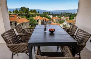 uma mesa com cadeiras e uma tigela de fruta na varanda em Villa Baden em Malinska