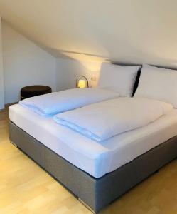 1 cama con sábanas blancas y almohadas en una habitación en Das Bergl en Rosegg