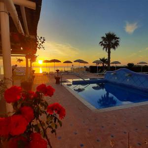 una puesta de sol sobre una piscina con flores rojas en Hotel Albatros, en Isquia