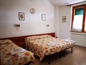 a hotel room with two beds and a window at Osteria dei Locandieri in Abbadia San Salvatore