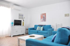 Una sala de estar con dos sofás azules y un televisor. en Apartamentos Las Rosas, en Denia