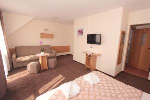 a hotel room with a couch and a television at Sunset Przymorze in Rewal