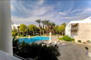 een zwembad met palmbomen en een gebouw bij Geffen royal park in Eilat