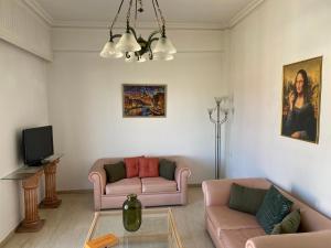 sala de estar con 2 sofás rosados y TV en Park, en Agioi Theodoroi