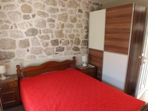 a bedroom with a red bed with a stone wall at Gudelj Apartments in Perast