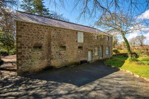 een bakstenen gebouw met een oprit ervoor bij The Coach House in Falmouth