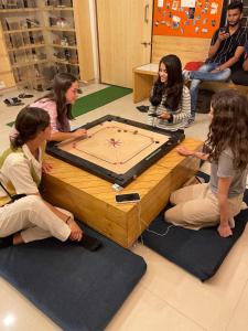 un grupo de chicas sentadas alrededor de una mesa con un juego en Nap Manor Hostels en Bombay