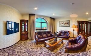 a living room with leather couches and a table at Plaza Hotel Bishkek in Bishkek