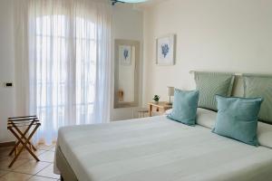 a white bedroom with a large bed with blue pillows at Torre Archirafi Vacanze in Riposto