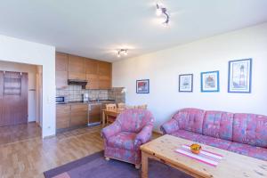 a living room with two couches and a table and a kitchen at Vogelsand 325 in Cuxhaven