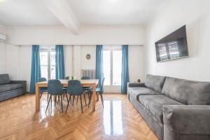 een woonkamer met een bank en een tafel en stoelen bij Victoria Sun Apartments in Athene
