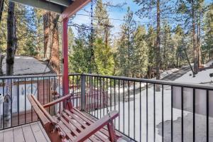 eine Veranda mit einer Bank und einem Geländer mit Bäumen in der Unterkunft Wolf Cub Cabin - 1946 by Big Bear Vacations in Big Bear Lake