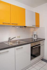 クックスハーフェンにあるHaus Knechtsand 431の白と黄色のキャビネットとシンク付きのキッチン