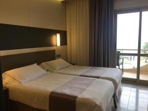 two beds in a hotel room with a window at Hotel las Dunas in Noja