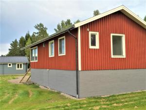 a red and grey house with a garage at Lakeview Houses Sweden - Red House in Svärdsjö