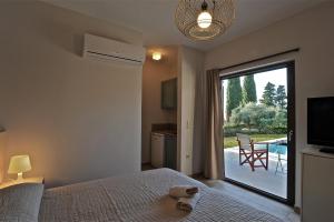 1 dormitorio con 1 cama y puerta corredera de cristal con patio en Elaia Villas, en Minia