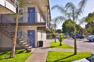 a building with blue doors and palm trees in a parking lot at Motel 6-Sacramento, CA - Central in Sacramento