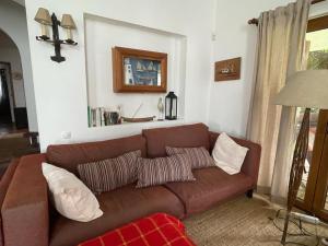 a living room with a brown couch with pillows at 4Sea House in Porto Covo