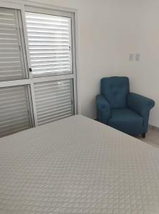 een slaapkamer met een bed en een blauwe stoel bij Mi Limonero in Esperanza