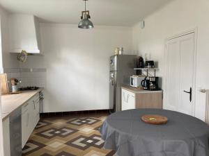 uma cozinha com uma mesa e um frigorífico em Gîte La Maison de JuJu em Lacave