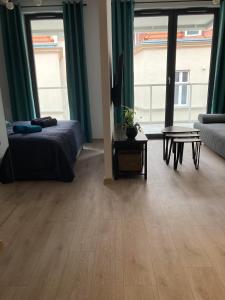 a room with a bed and a table and windows at Apartament Wrzeszcz, Kamienice Kołłątaja in Gdańsk