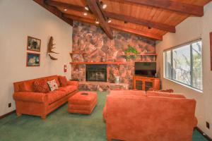 a living room with orange furniture and a stone fireplace at La Cerena Getaway #1960 by Big Bear Vacations in Big Bear Lake