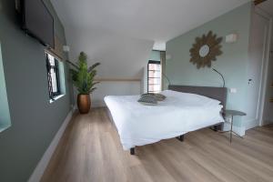 a bedroom with a bed and a tv on a wall at The Lake Inn in Nieuwkoop