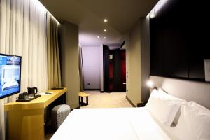 ヴロラにあるThe Central View Boutique Hotelのベッドとテレビが備わるホテルルームです。