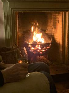 a person holding a glass of wine in front of a fireplace at Kilmorie House in Elgin