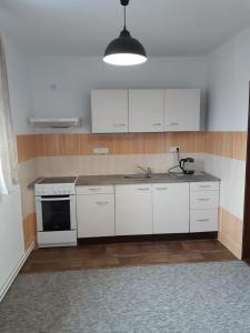 a kitchen with white cabinets and a stove at Černá v Pošumaví Apartmán in Černá v Pošumaví +11 photos