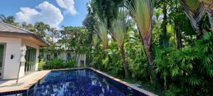 ein Pool vor einem Haus mit Palmen in der Unterkunft Beautiful villa walking distance from Bangtao Beach in Strand Bang Tao