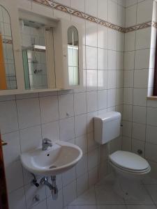 a white bathroom with a toilet and a sink at Apartment Smajlovic in Kukci