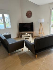 a living room with two chairs and a flat screen tv at Le gîte des vosges in Fraize