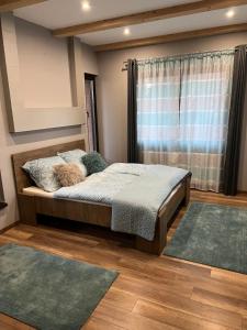 a bedroom with a bed and a window with rugs at Anita Apartman Miskolctapolca in Miskolc