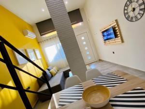 a living room with a table and chairs and a clock at 48 Downtown Lofts in Nea Peramos