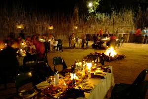 un grupo de personas sentadas en mesas en un restaurante por la noche en Timbavati Safari Lodge en Mbabat