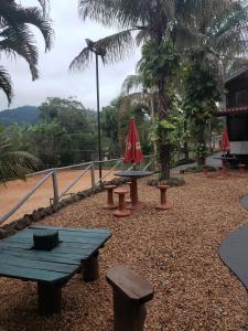 圣代佩德罗Cabana Hostel Sobrado EcoPark的一组野餐桌和红色伞
