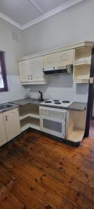 cocina con fogones y suelo de madera. en Fairfield Guest House, en Pietermaritzburg