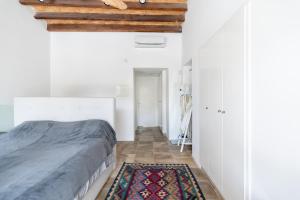 a bedroom with white walls and a bed and a rug at To Hani - Kamara Maisonette in Nicosia