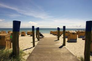 a wooden boardwalk on a beach with chairs and the ocean at Ferienwohnung Schattschneider in Burgtiefe auf Fehmarn 