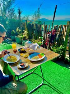 a man sitting at a picnic table with food on it at Golden King Guest in Nuwara Eliya
