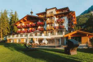 un gran edificio con mesas y sillas delante de él en Hotel Lindenhof en Ramsau am Dachstein