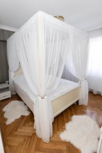 a bedroom with a bed with white curtains and rugs at ALPASIO RENTALS in Galaţi