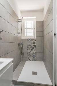 a bathroom with a shower with a sink and a window at To Hani - Small Studio in Nicosia