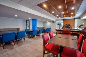um restaurante com mesas de madeira e cadeiras azuis em Holiday Inn Express Fairfax-Arlington Boulevard, an IHG Hotel em Fairfax