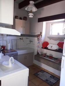 a white kitchen with a sink and a window at La maison du Mas Rando in Saint-Georges-Nigremont