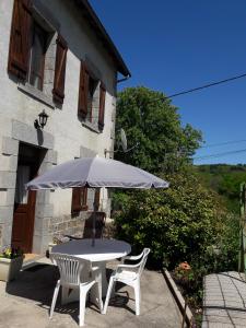 a table and two chairs and an umbrella in front of a building at La maison du Mas Rando in Saint-Georges-Nigremont +9 photos