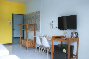a living room with a table and a tv on a wall at Talavera Hostel in Phitsanulok